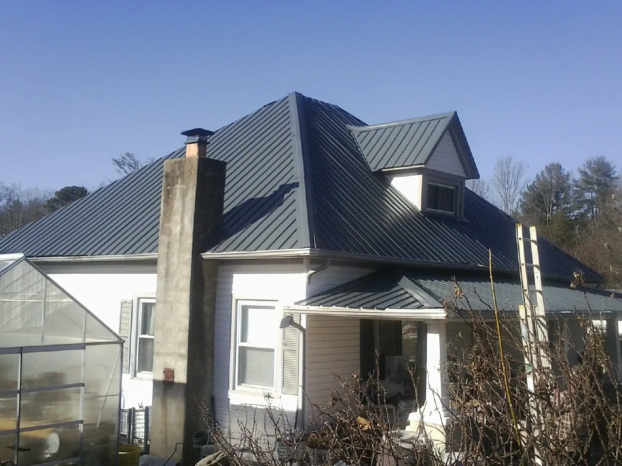 Dark blue standing seam metal roof on a white farmhouse with dormer — Slate & Tile Roof Repair by Roofing Brothers in South Windsor