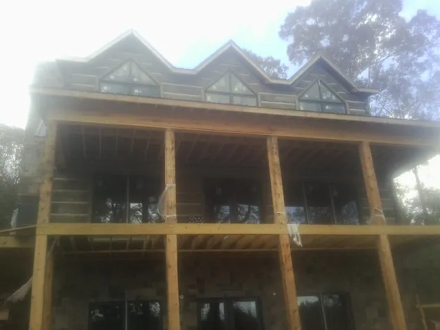 Dormers and porch framing on a large log home under construction — Roof Coating work by our crew in South Windsor