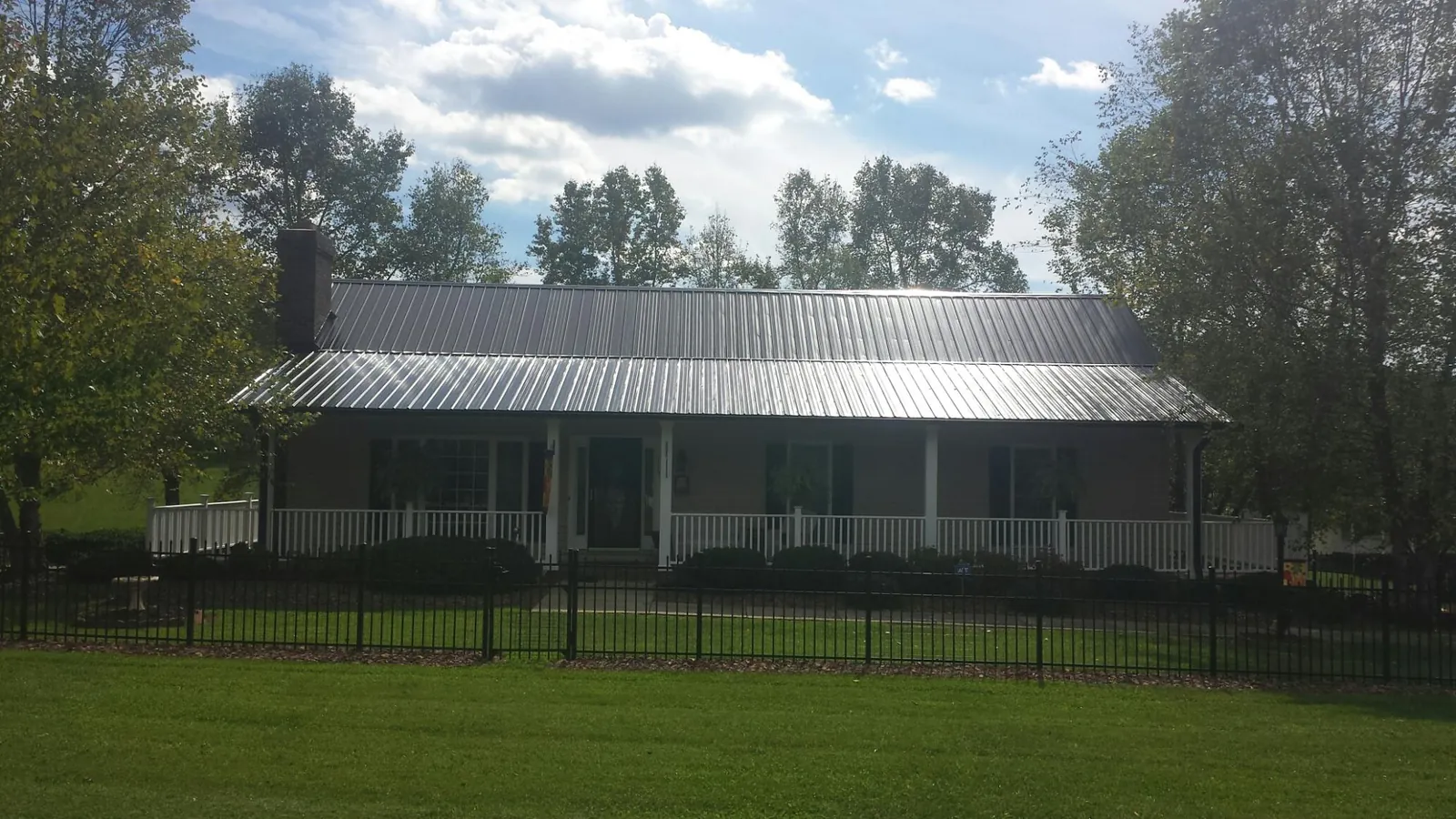 Gray metal roof on a brick ranch with a full width front porch — Gutter Guard Installation work by our crew in South Windsor