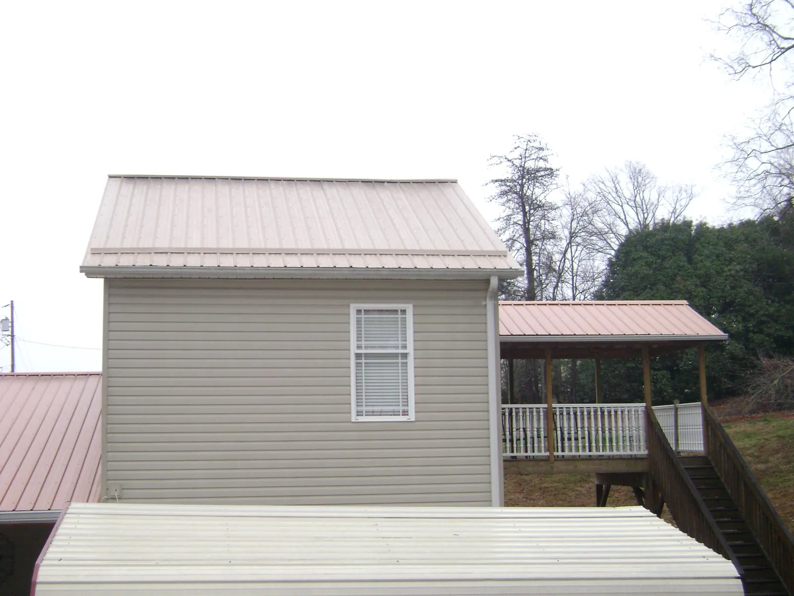 Tan metal roofs on a two story addition and attached porch, from a Roof Replacement job in South Windsor