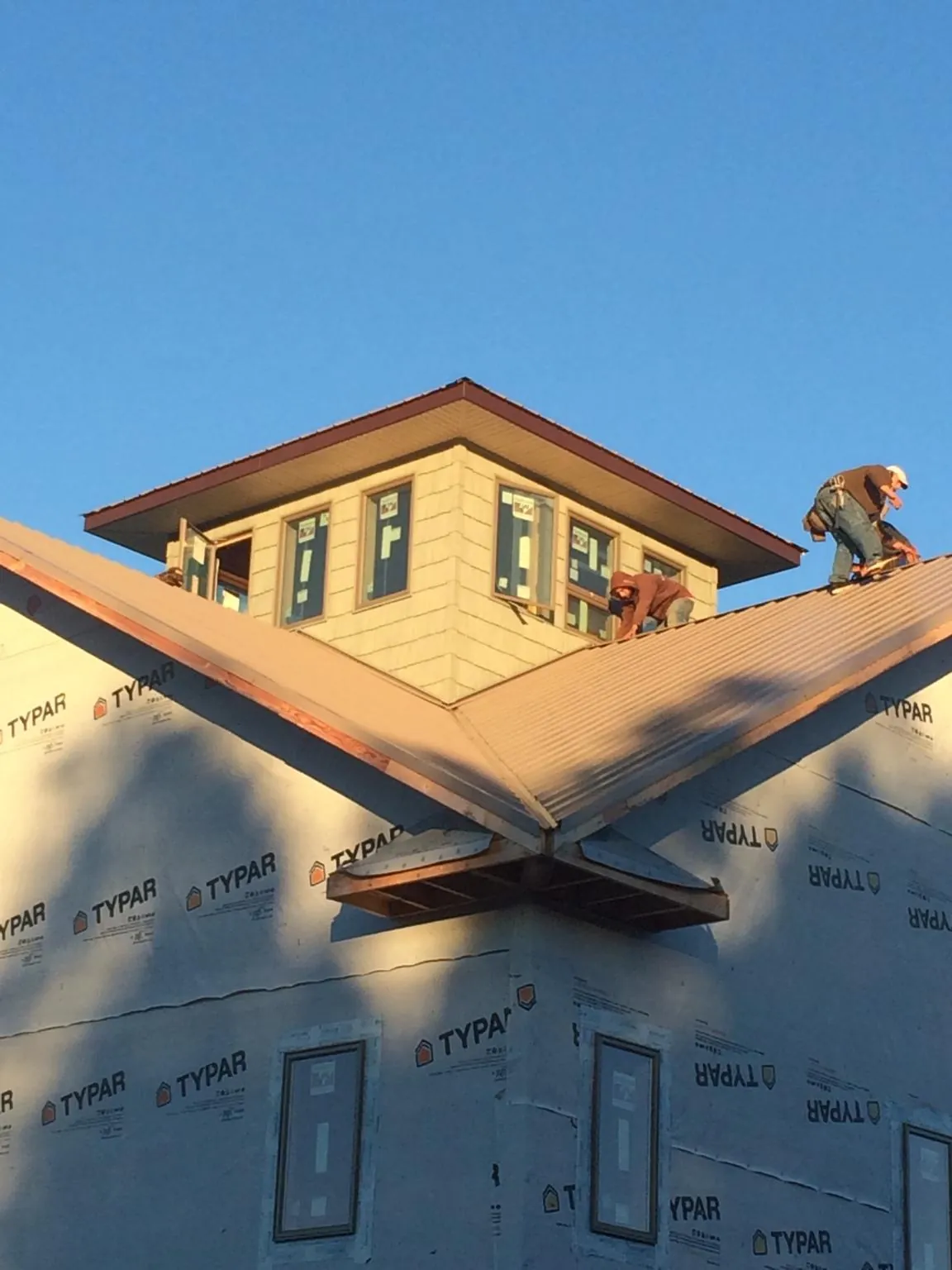 Roofers working around a rooftop cupola on a new metal roof at sunset — Roof Waterproofing in South Windsor by Roofing Brothers